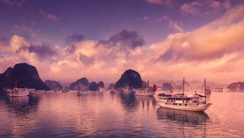 Tour and cruise boats among the karst formations in Halong Bay, Vietnam.